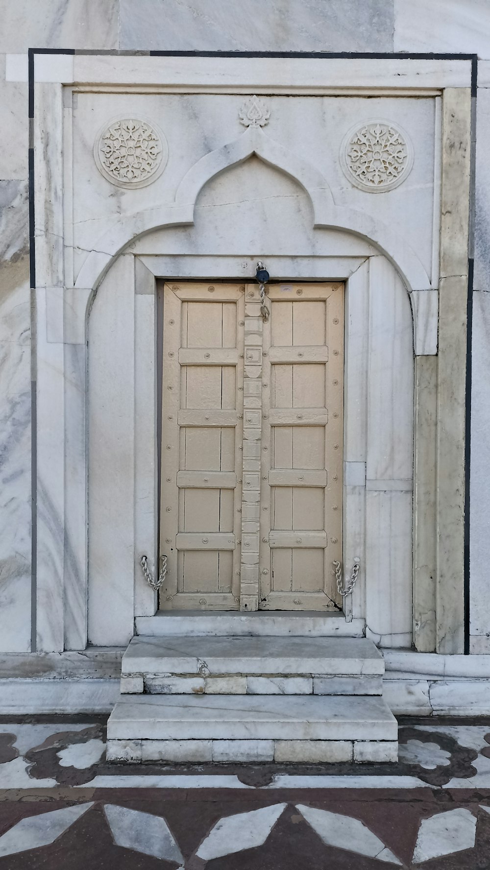 a white marble building with two wooden doors