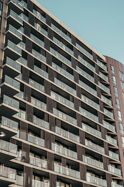 Modern condo building exterior with balconies and city skyline in the background.