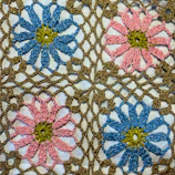 a close up of a crocheted doily with flowers on it