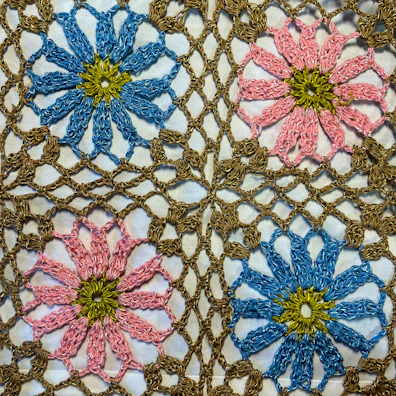 a close up of a crocheted doily with flowers on it