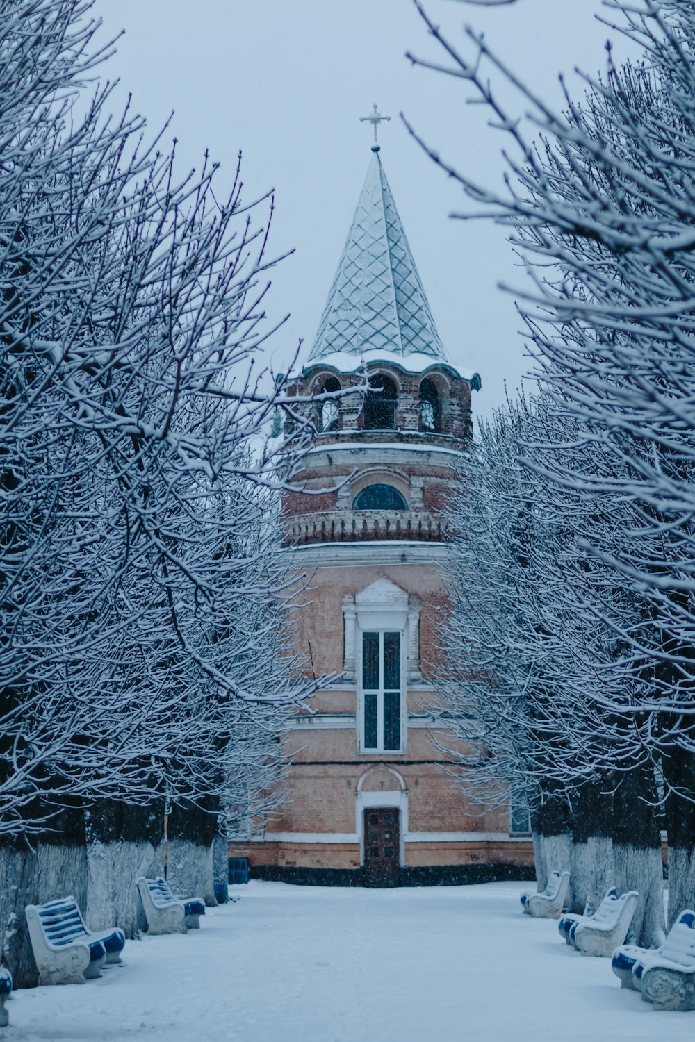 a tower with a clock in the middle of a snowy park