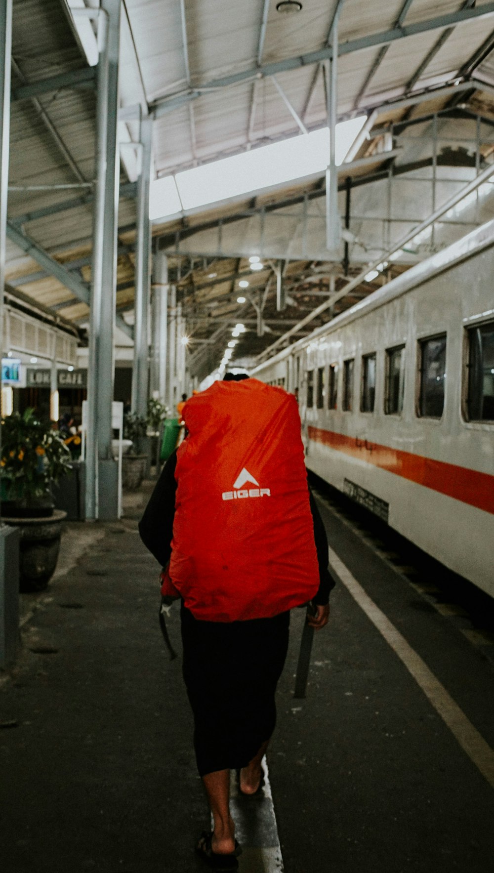 a person with a red jacket walking towards a train