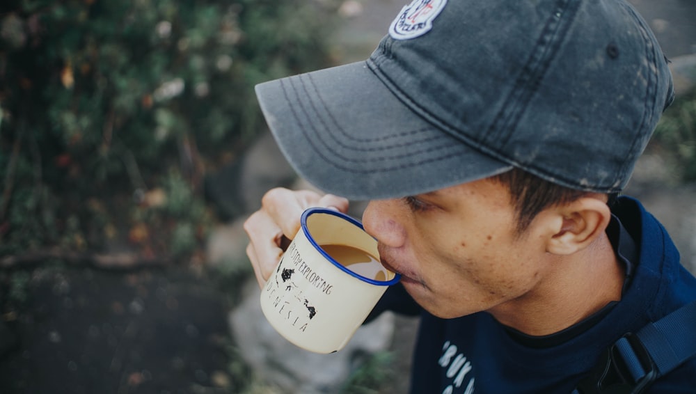 a man wearing a hat drinking from a coffee mug
