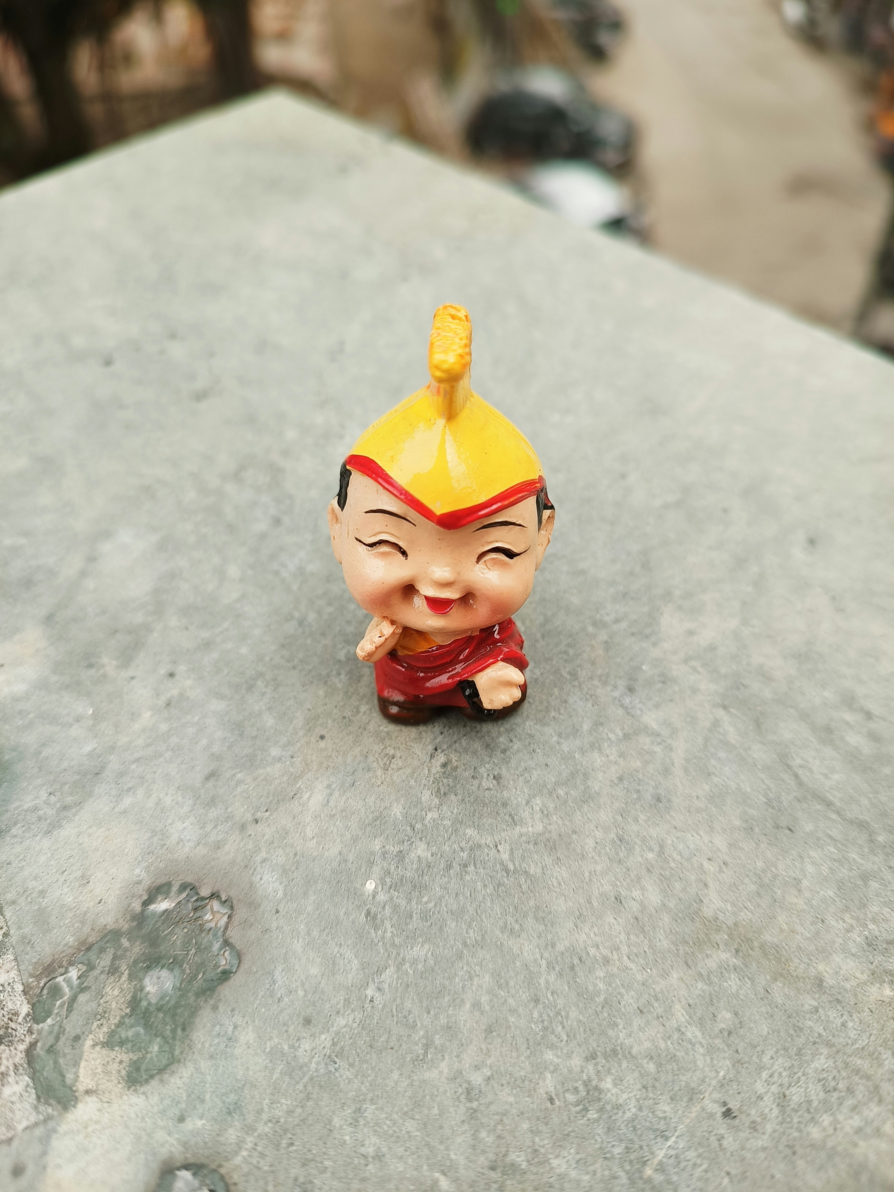 a small figurine sitting on top of a cement slab