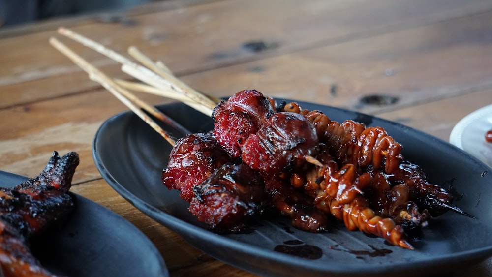 a black plate topped with meat covered in sauce