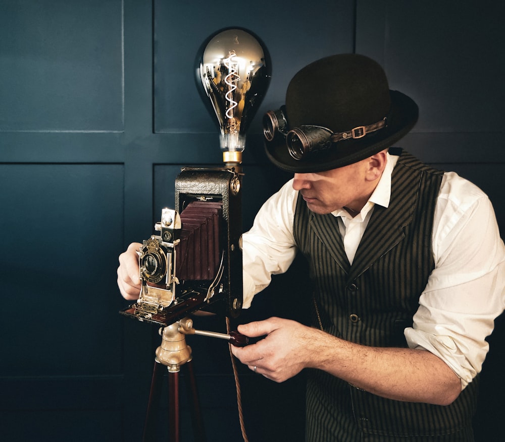 a man in a top hat is looking at an old fashioned camera