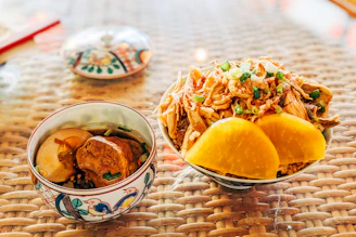 two bowls of food on a table with chopsticks