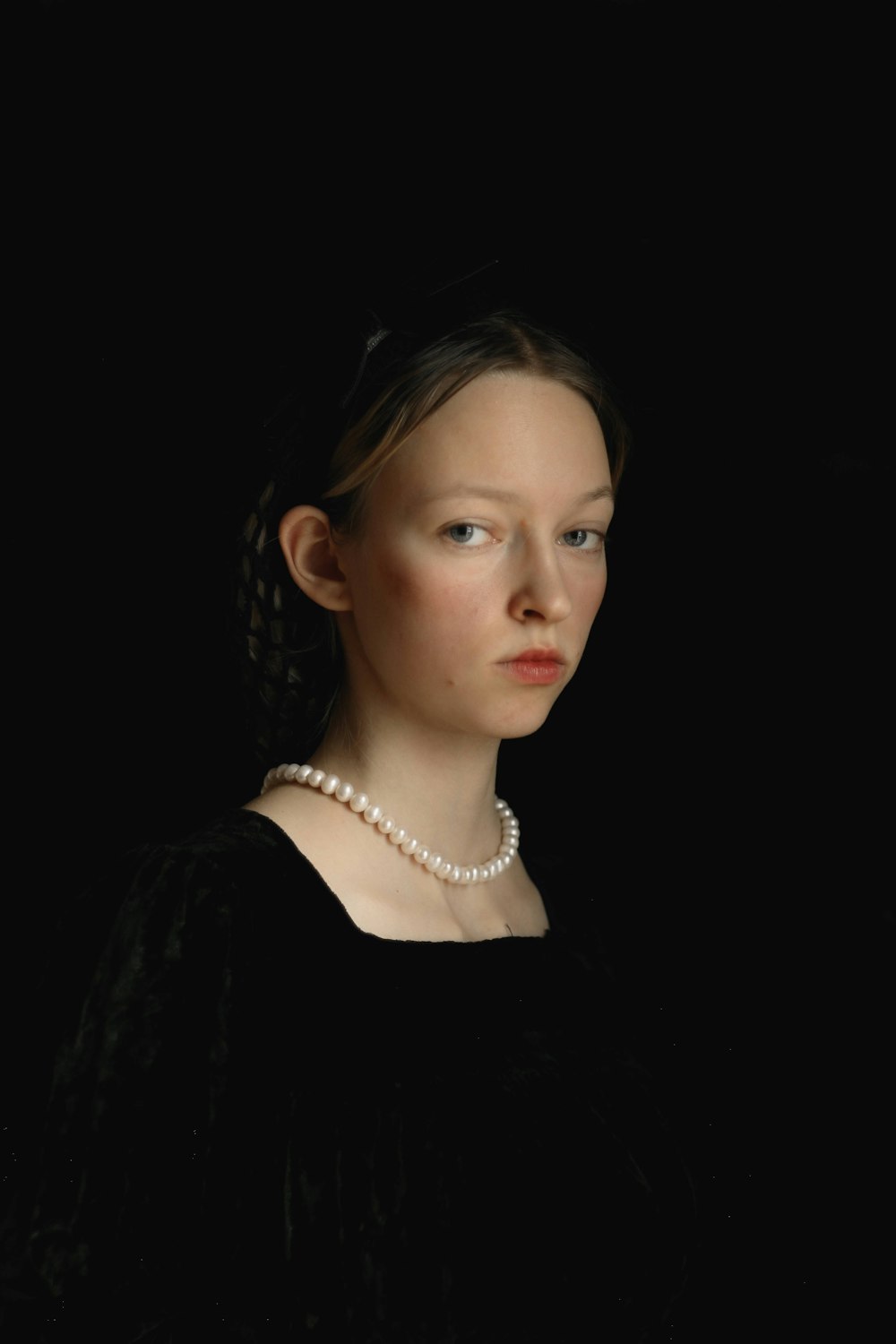 a woman in a black dress with a pearl necklace