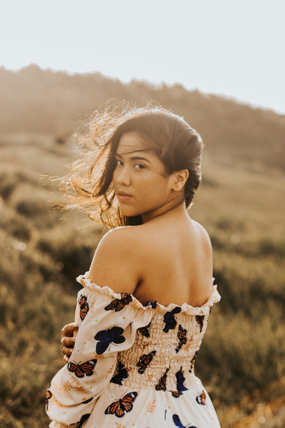 a woman standing in a field with her hair blowing in the wind