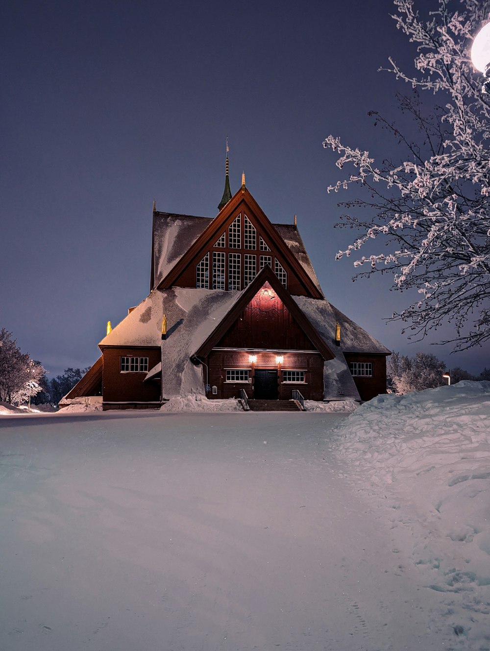 a snow covered house with a full moon in the background