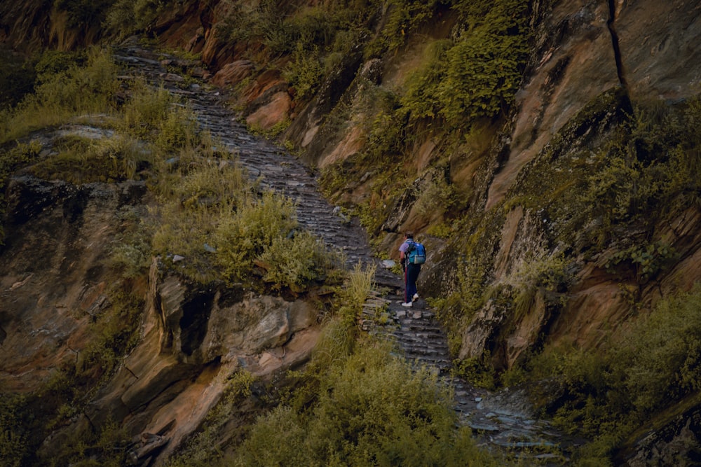 Un hombre caminando por un empinado sendero de montaña