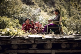 An elder and child sharing stories in a Lithuanian countryside setting with rolling hills.