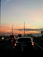 A tow truck quickly lifting a stranded car on a busy highway at sunset.