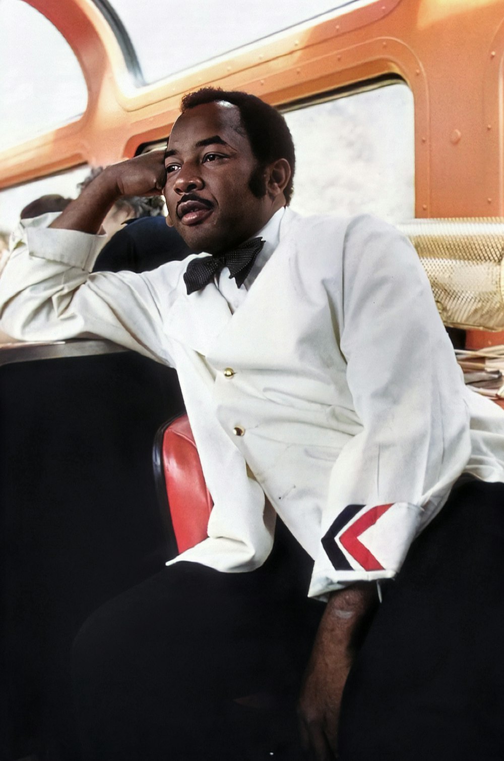 a man in a white suit sitting on a train