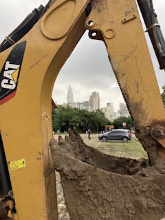 Backhoe digging foundation trenches with a city skyline in the background