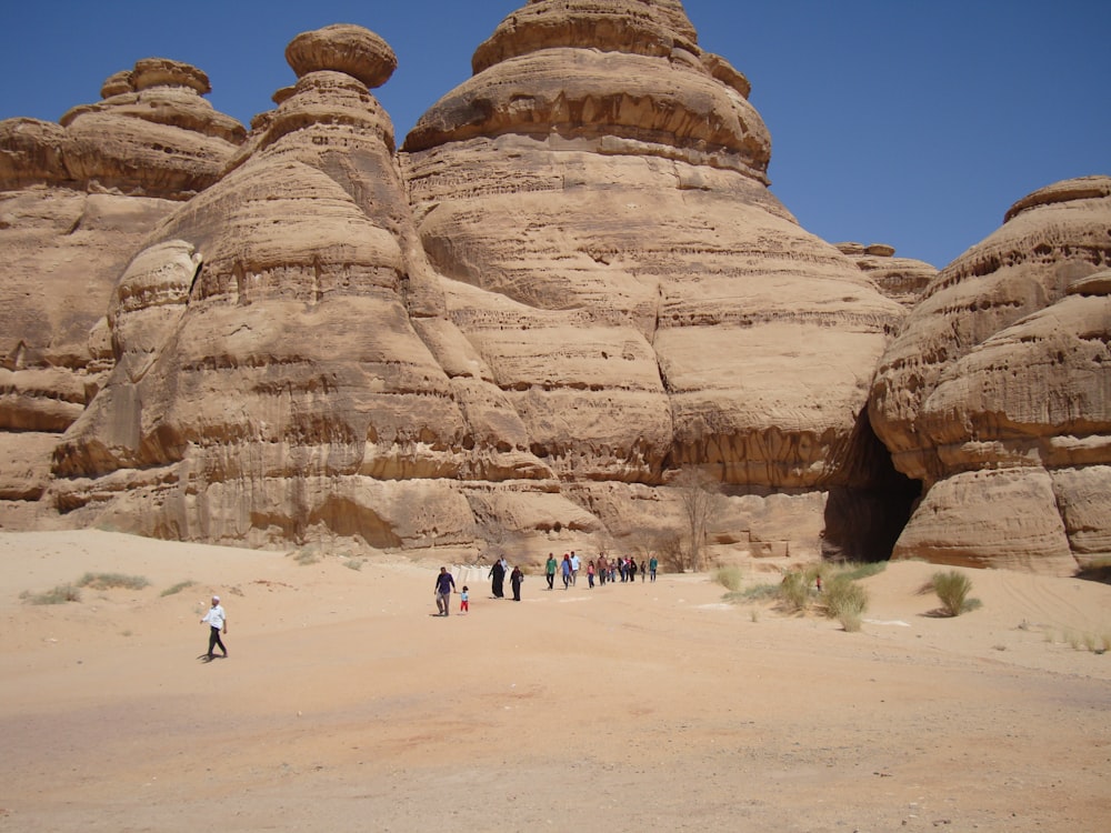 a group of people standing in front of a rock formation