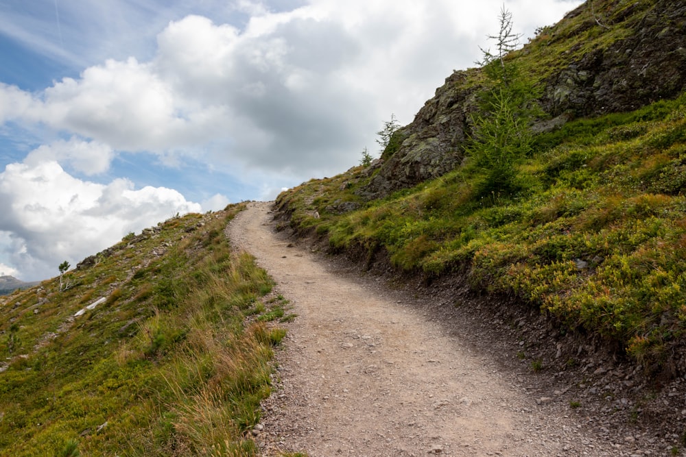 a dirt road going up a grassy hill