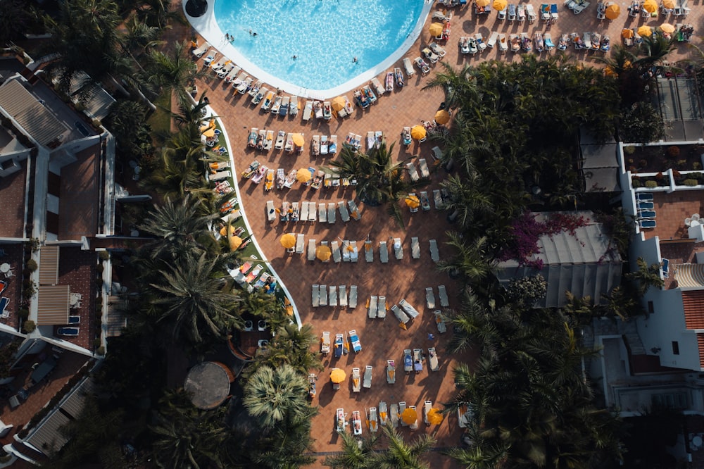 an aerial view of a resort pool with chairs and umbrellas