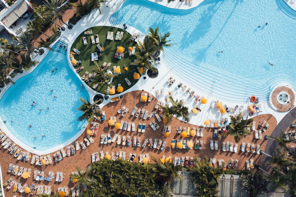 an aerial view of a resort pool with chairs and umbrellas