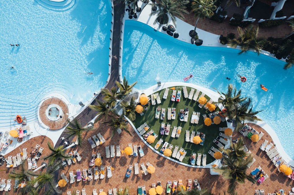 an aerial view of a pool with chairs and umbrellas