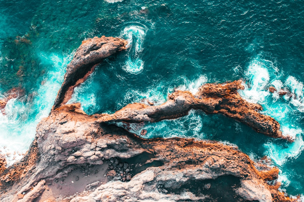 an aerial view of the ocean and rocks