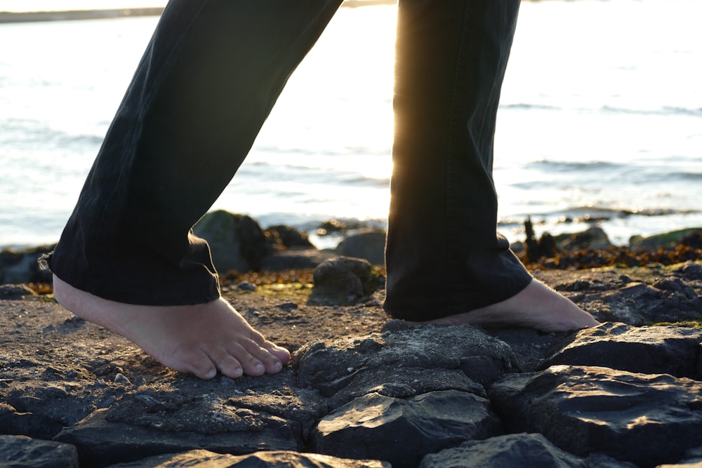 a person standing on a rocky beach next to the ocean