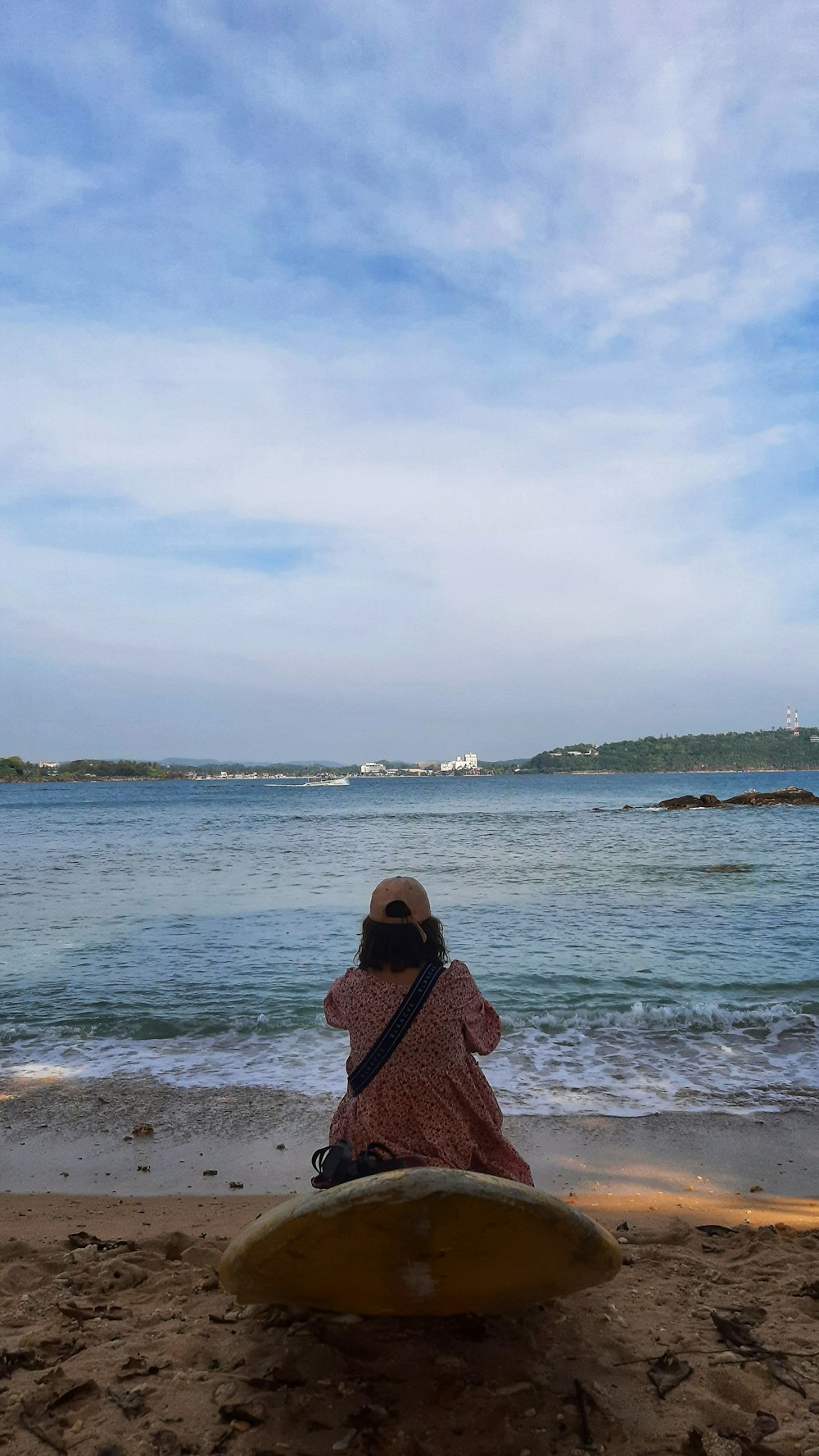 a woman sitting on top of a surfboard on a beach