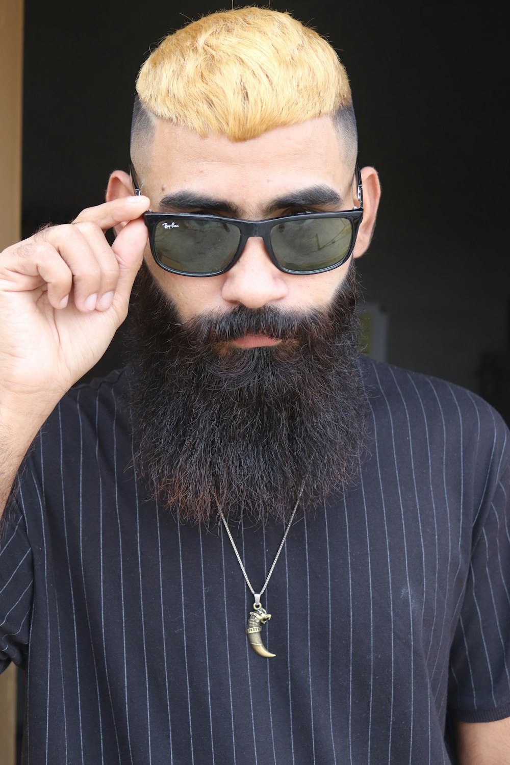 um homem com um cabelo amarelo e barba usando óculos escuros