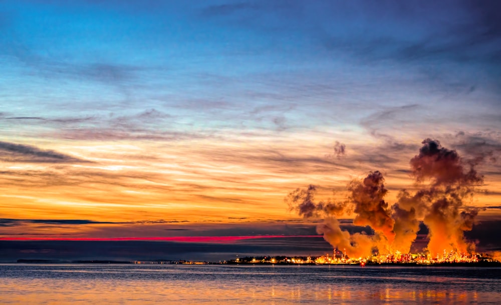 a large plume of smoke rising from a large body of water