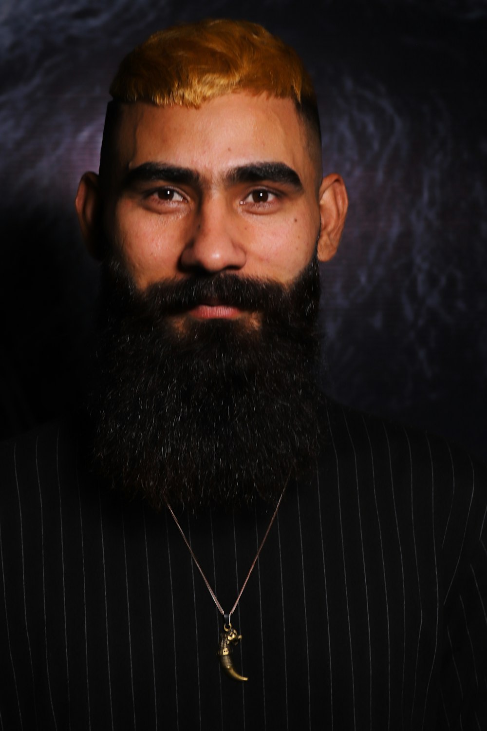 a man with a beard wearing a suit and a necklace