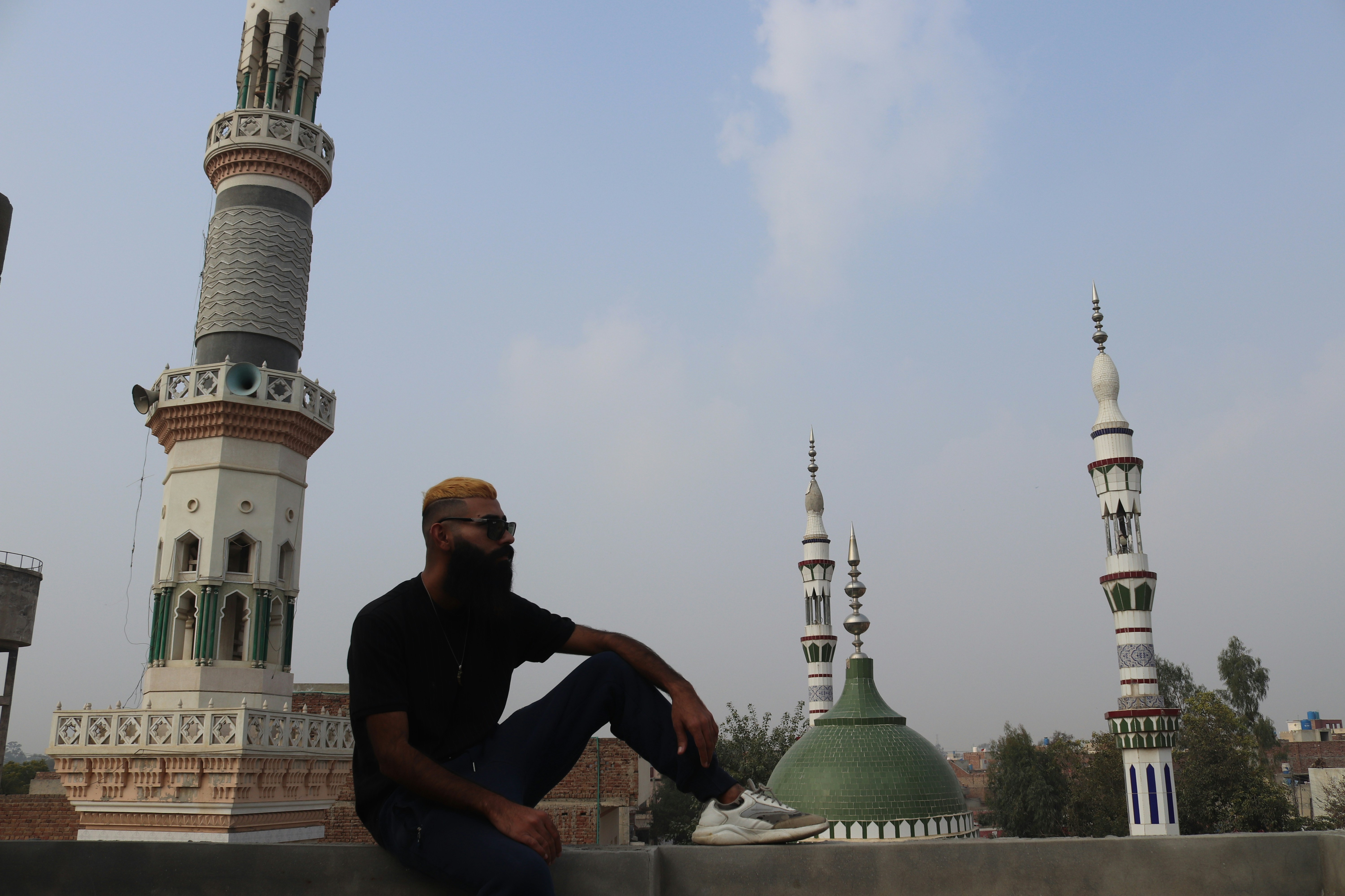 seorang pria duduk di langkan di depan masjid