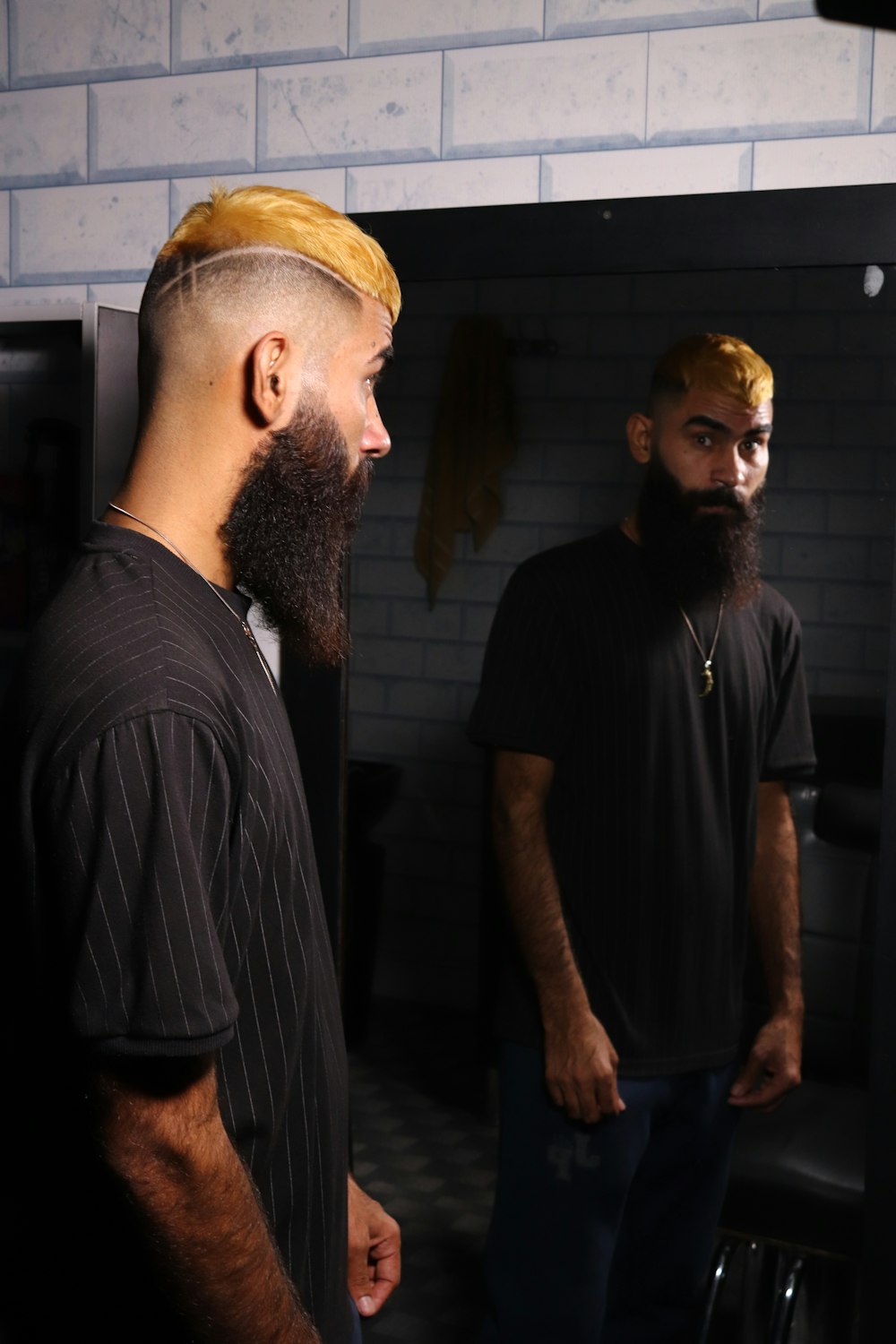a man with a long beard and a bald head standing in front of a mirror