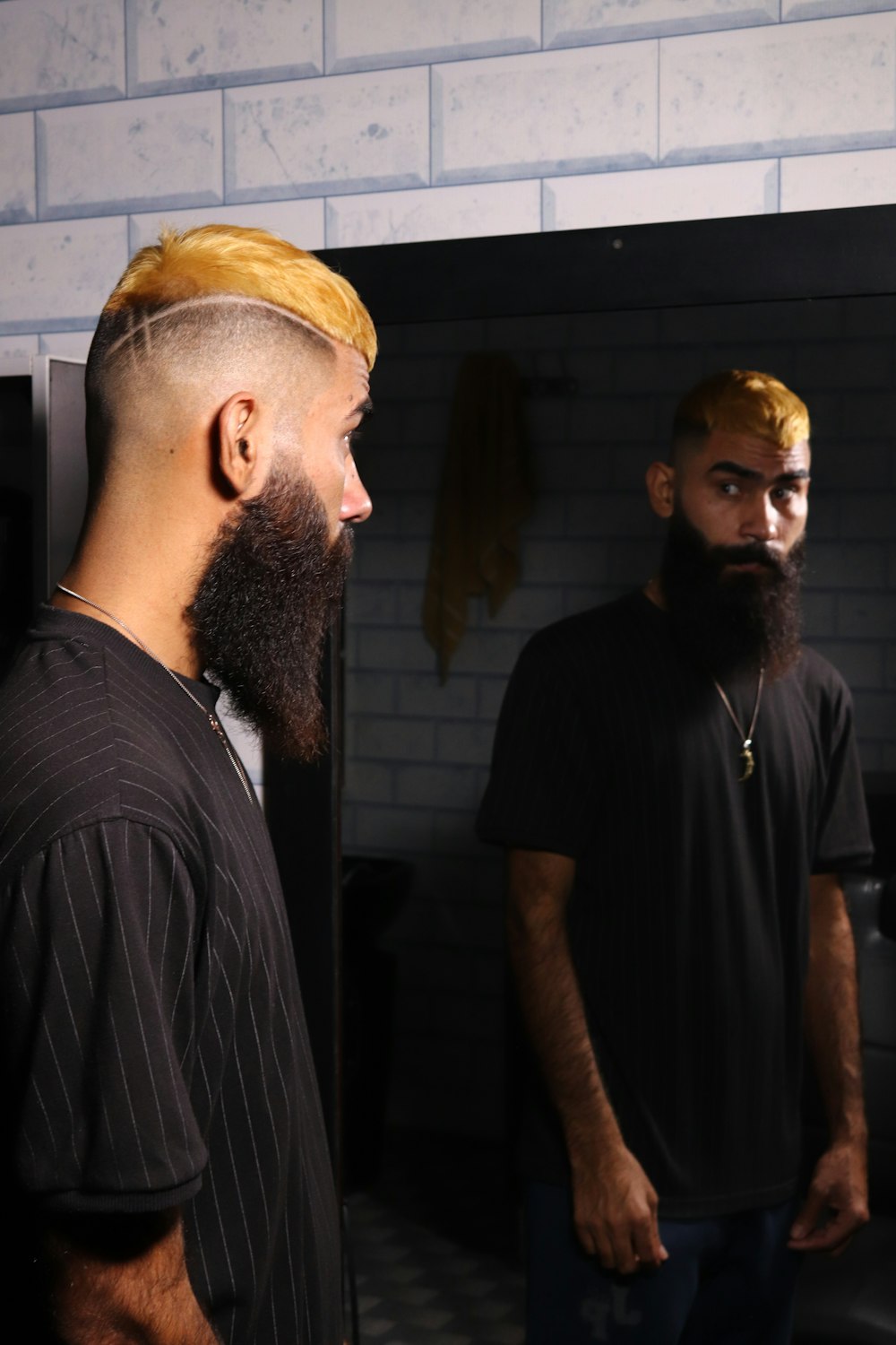 a man with a long beard and a bald head standing in front of a mirror