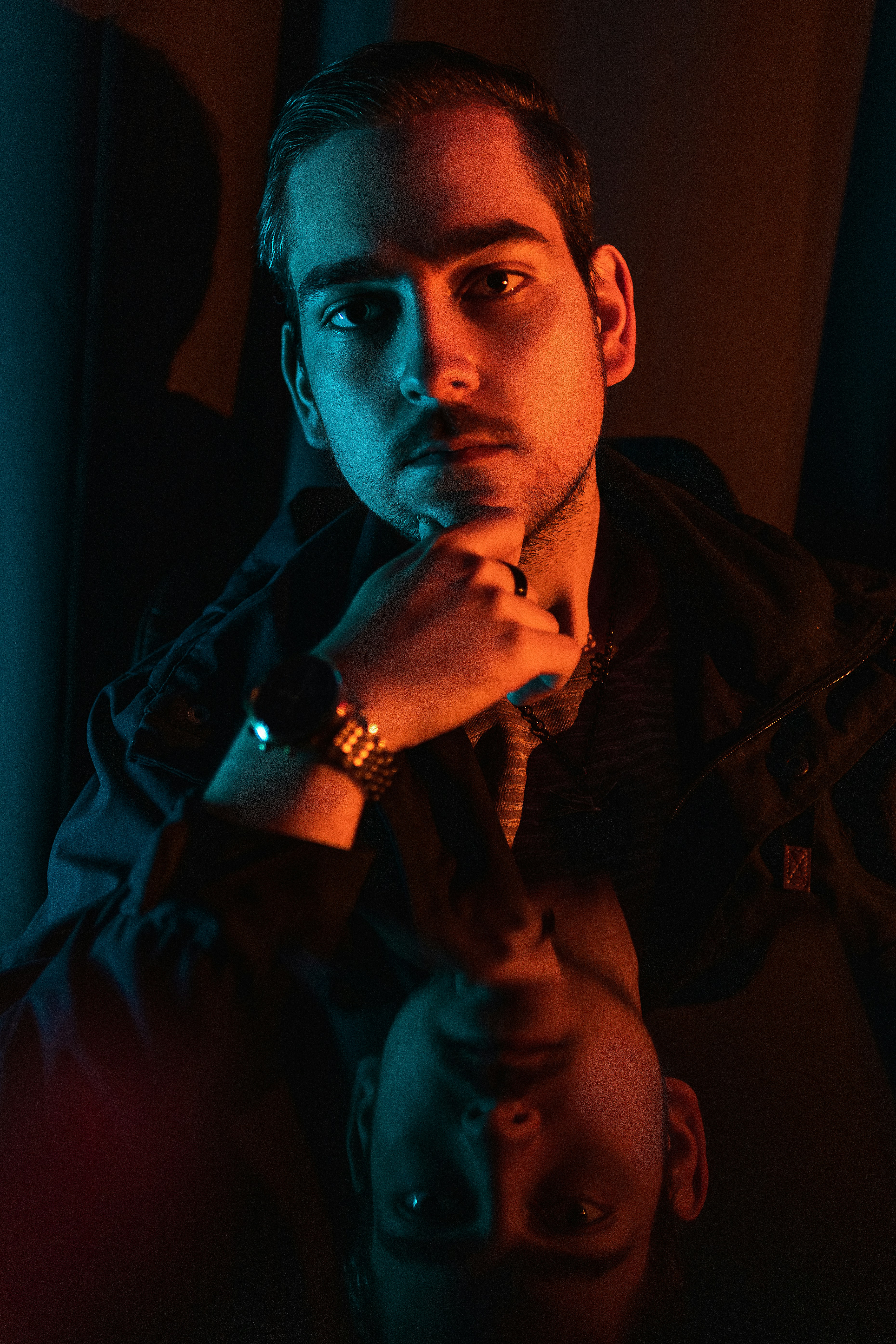 a man sitting in front of a mirror with his hand on his chin