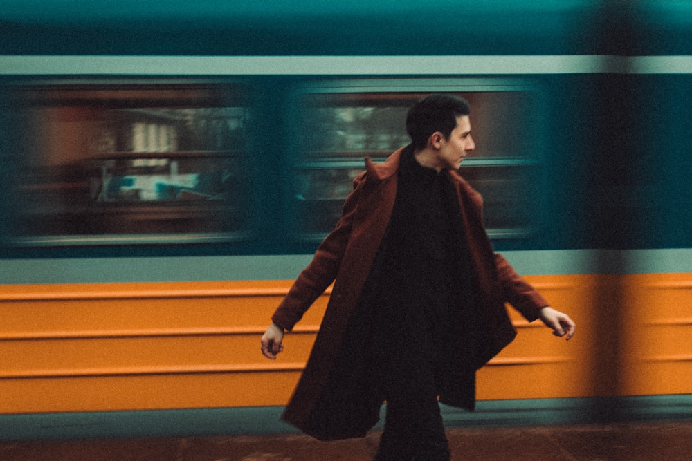 a man walking down a sidewalk next to a train