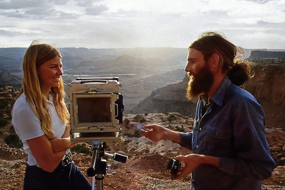 a man and a woman standing in front of a camera