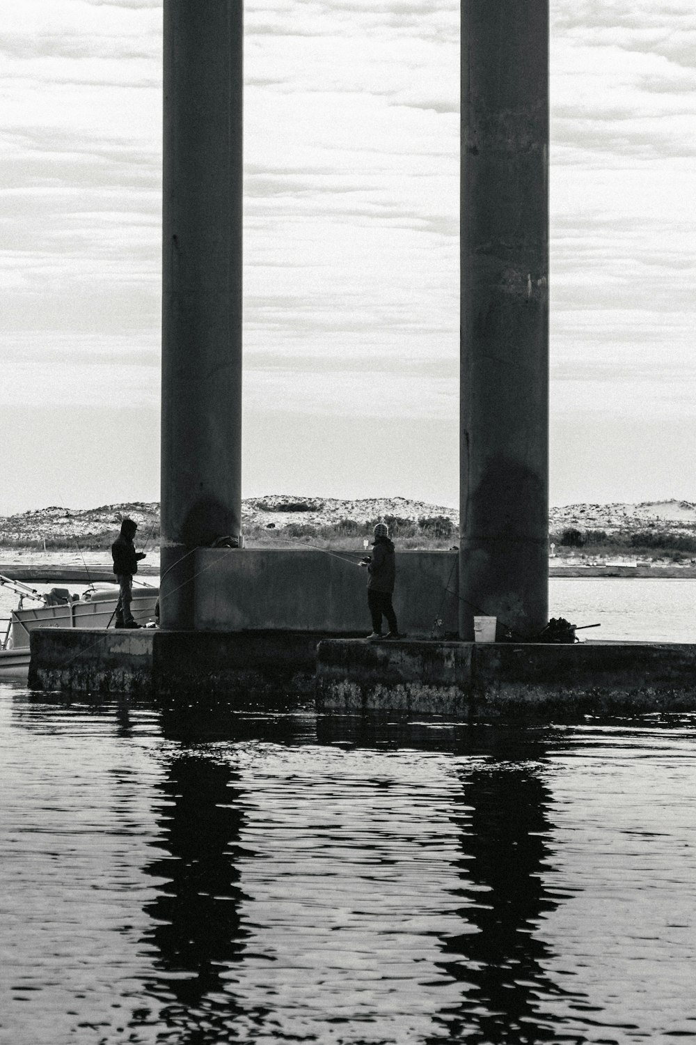 a couple of people standing on a pier next to a body of water