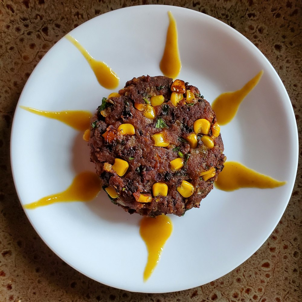 a white plate topped with a burger covered in sauce