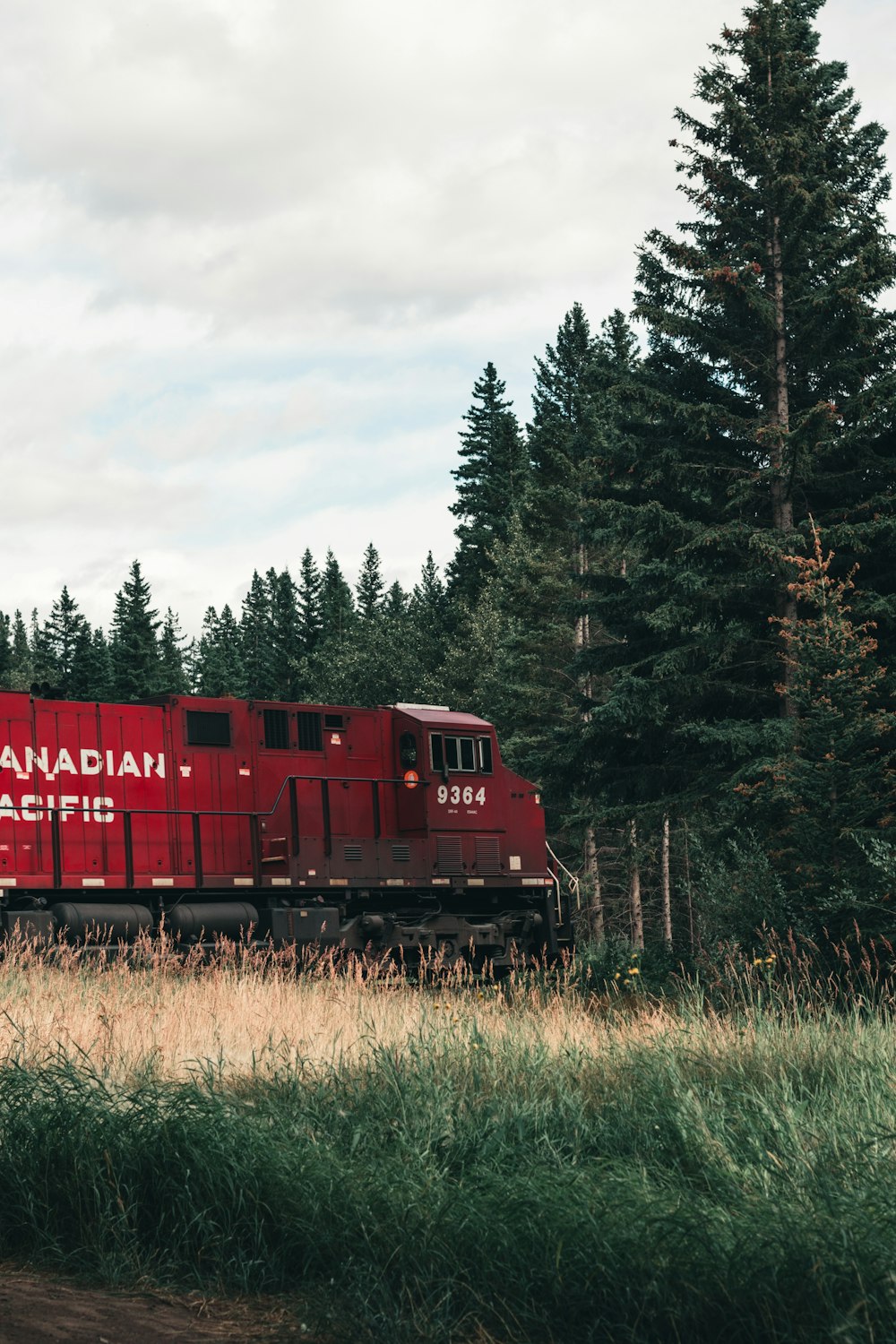 um trem viajando pelos trilhos do trem perto de um campo