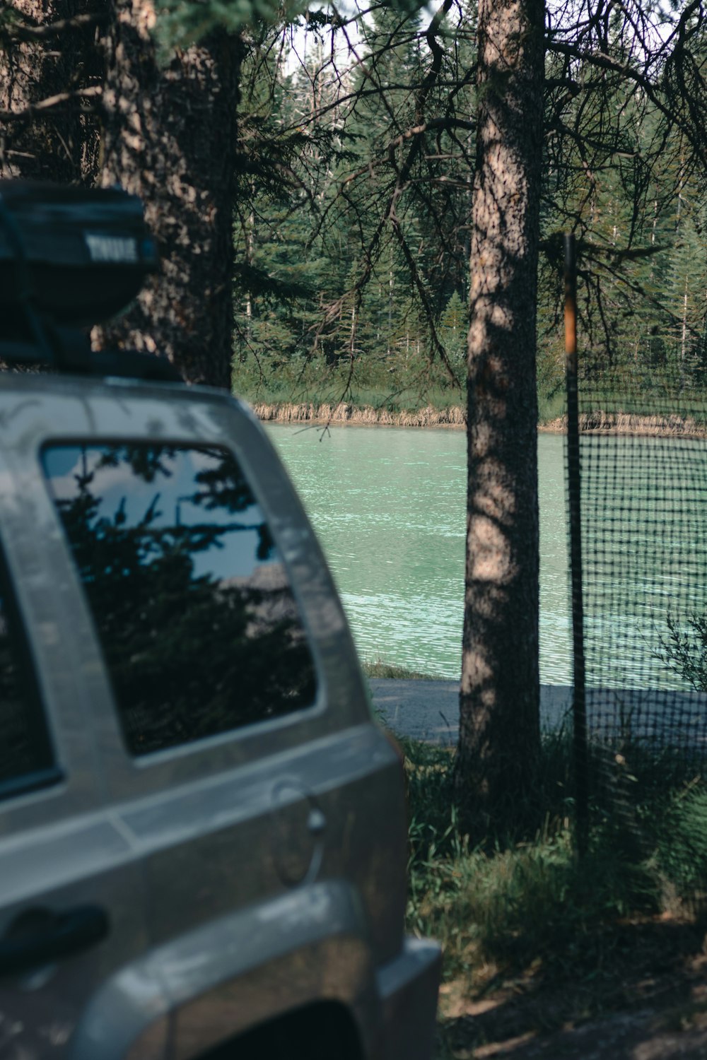 un'auto parcheggiata vicino a un albero vicino a uno specchio d'acqua