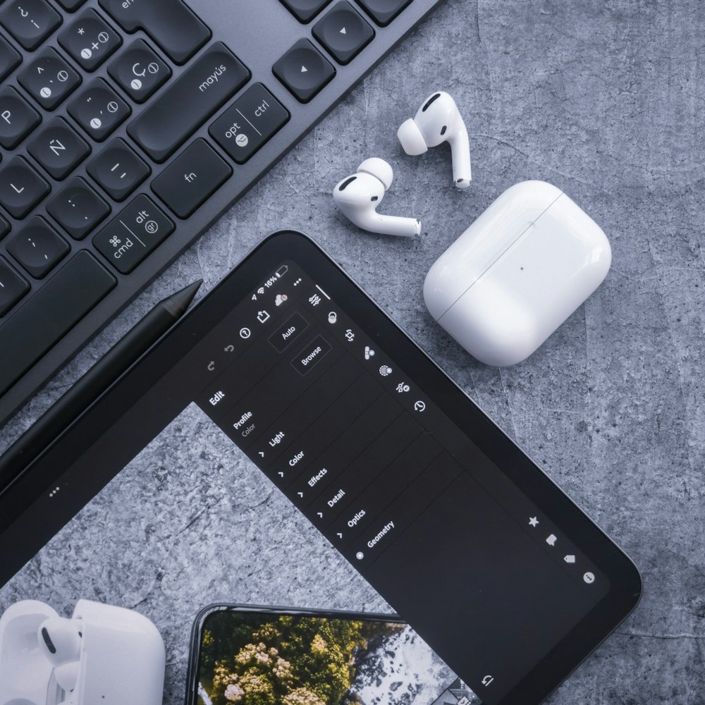 Un iPhone, auriculares y teclado en una mesa