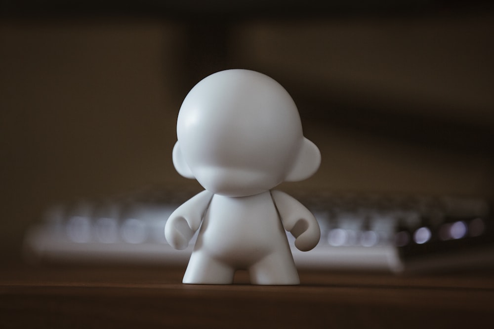 a small white figurine standing in front of a keyboard