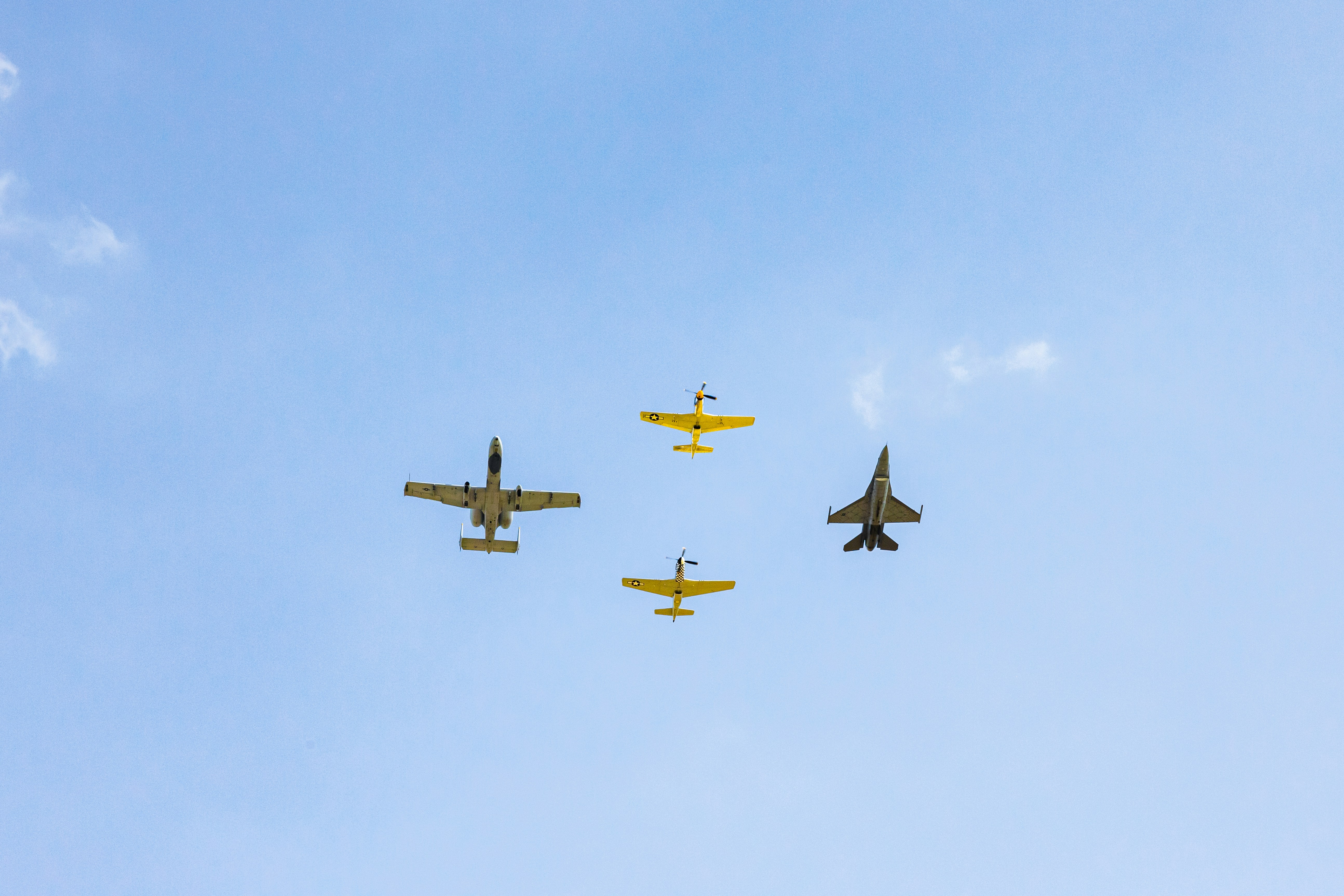 a group of four planes flying through a blue sky