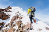 a man climbing up the side of a snow covered mountain