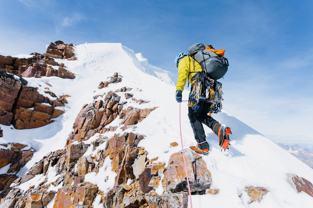 a man climbing up the side of a snow covered mountain