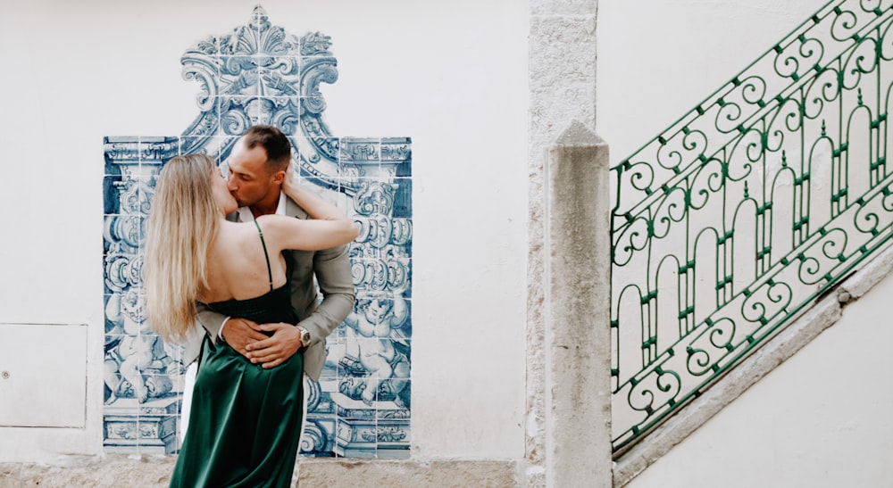 a man and a woman embracing in front of a blue and white wall