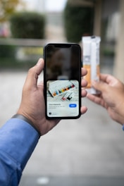 a person taking a picture of a cigarette with a cell phone