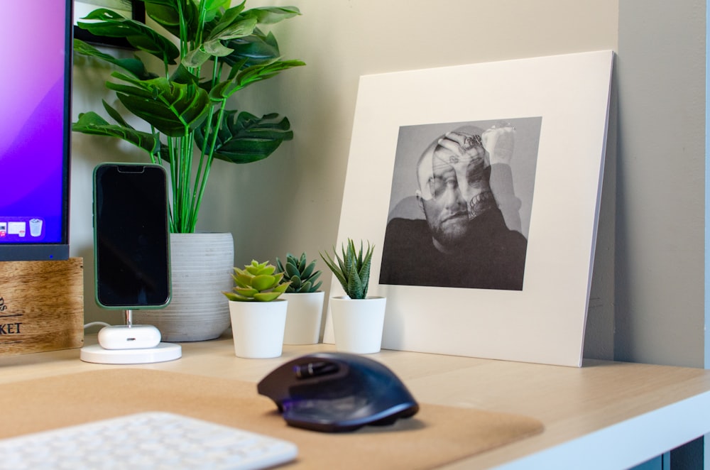 a desk with a computer monitor, mouse and a picture of a man