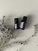 two bottles of essential oils sitting next to a plant