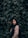 a woman standing in front of a wall of leaves